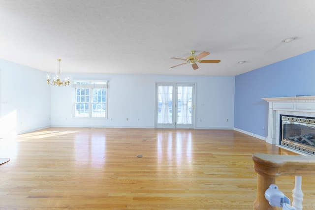 unfurnished living room with light wood-style flooring, plenty of natural light, and a glass covered fireplace