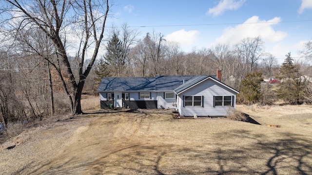 single story home featuring a front lawn, dirt driveway, and a chimney