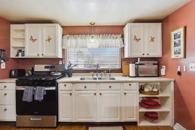 kitchen featuring open shelves, white cabinets, gas stove, and a sink