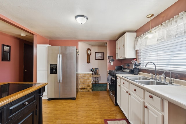 kitchen featuring a sink, stainless steel appliances, white cabinetry, and light countertops