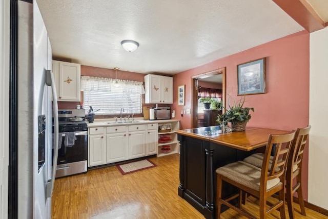 kitchen featuring a sink, stainless steel appliances, white cabinets, and light wood finished floors