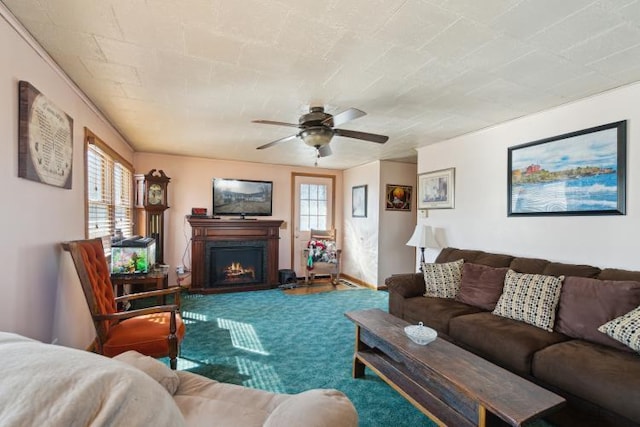 carpeted living room with a ceiling fan and a lit fireplace