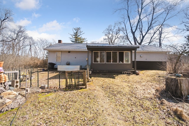 rear view of property featuring fence, a chimney, and metal roof