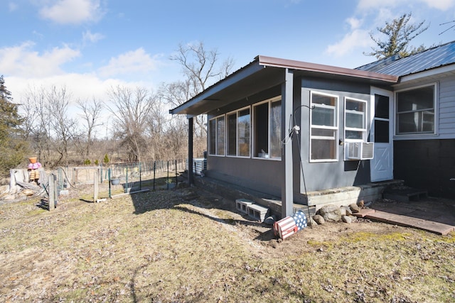 view of side of property with entry steps, metal roof, a sunroom, and fence