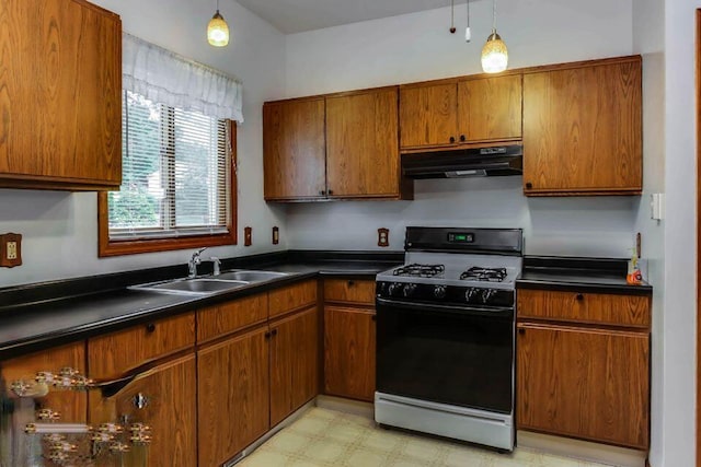 kitchen featuring under cabinet range hood, dark countertops, brown cabinetry, light floors, and black range with gas stovetop