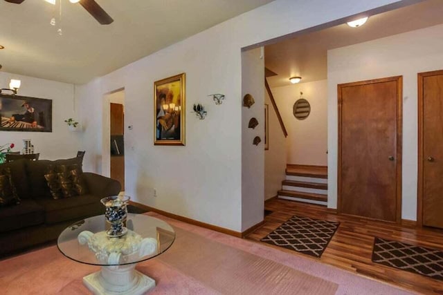 living area with stairs, wood finished floors, baseboards, and a ceiling fan