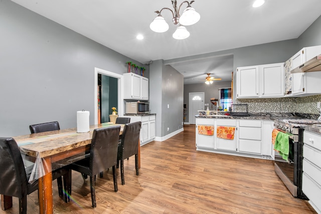 kitchen featuring light wood-style flooring, tasteful backsplash, white cabinetry, a peninsula, and appliances with stainless steel finishes