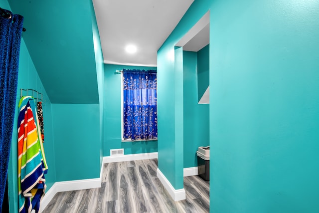 bathroom featuring visible vents, baseboards, wood finished floors, and vaulted ceiling