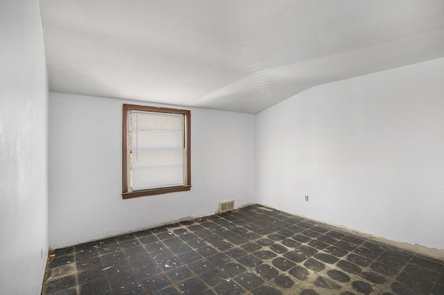 unfurnished room featuring tile patterned floors, visible vents, and lofted ceiling