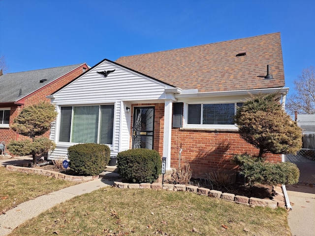 bungalow-style home with brick siding, roof with shingles, and a front lawn