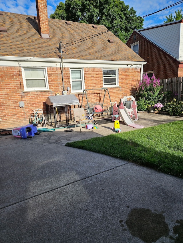 rear view of house with fence, a shingled roof, a chimney, and a patio area