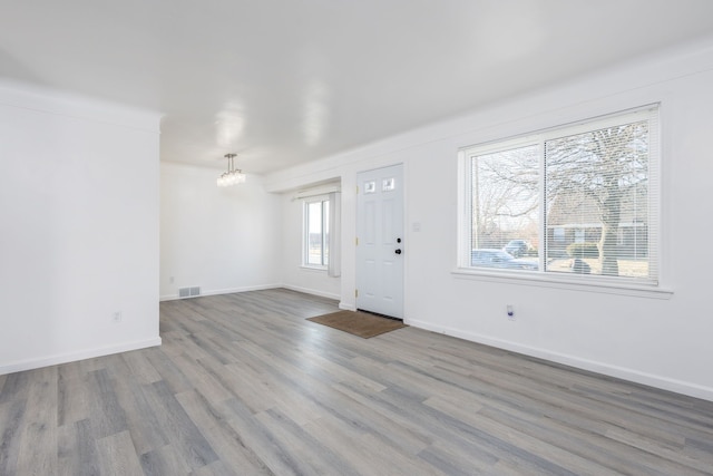 entryway with visible vents, baseboards, an inviting chandelier, and wood finished floors