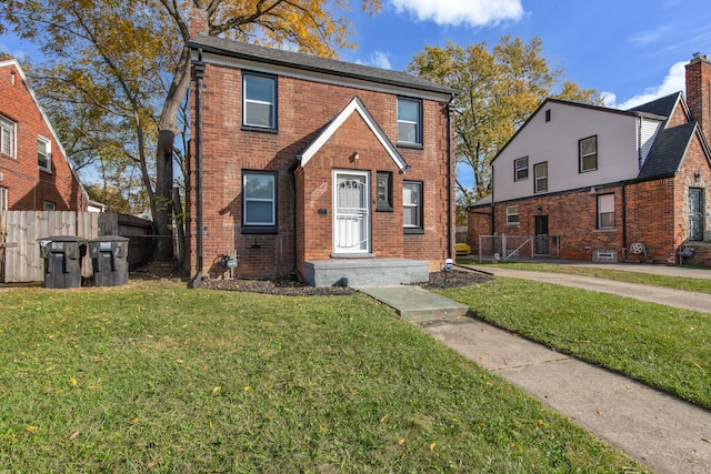 view of front of home with brick siding, a front lawn, and fence