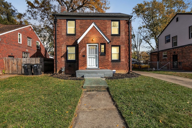 traditional home featuring a front yard, fence, brick siding, and a chimney