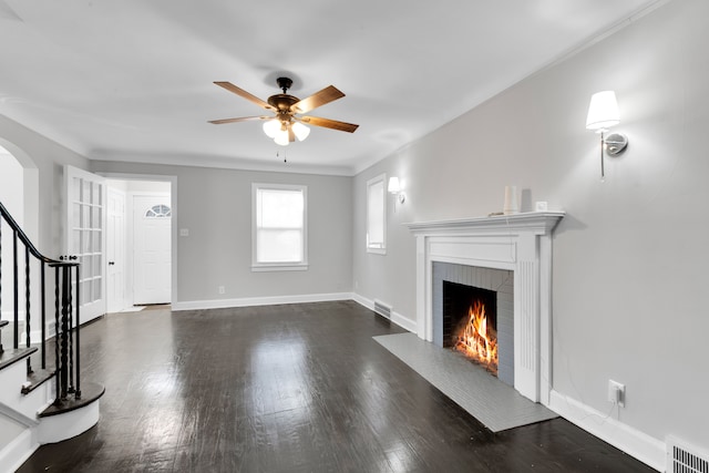 unfurnished living room with dark wood finished floors, a fireplace with flush hearth, arched walkways, and visible vents