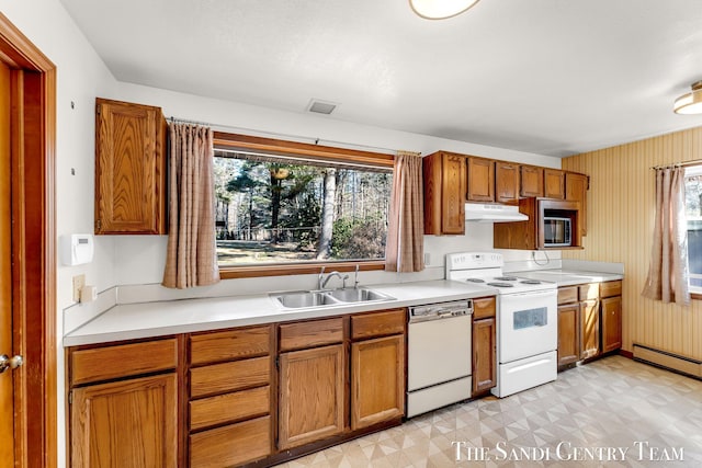 kitchen featuring under cabinet range hood, a sink, white appliances, light countertops, and light floors