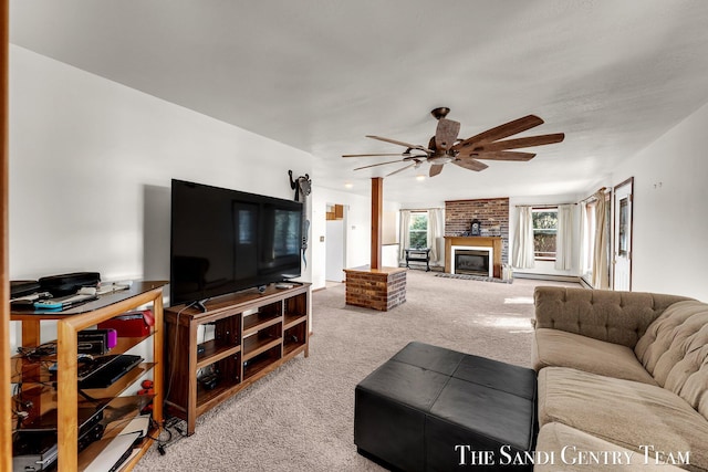 carpeted living room with a baseboard radiator, a large fireplace, and a ceiling fan