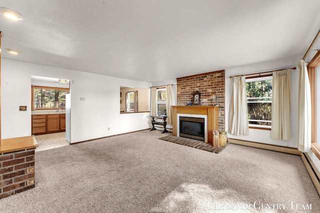 unfurnished living room featuring a wealth of natural light, a glass covered fireplace, baseboards, and carpet