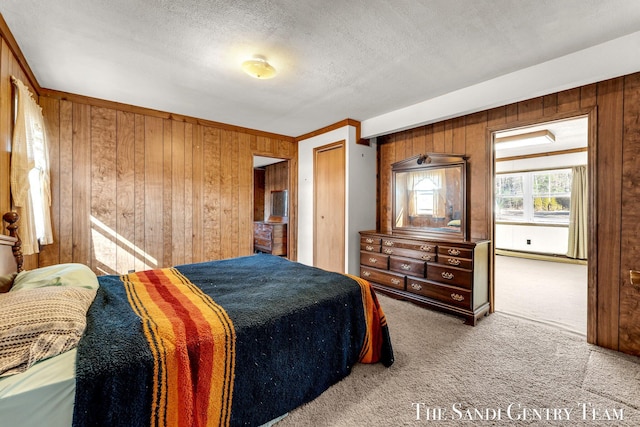 bedroom with wooden walls, carpet floors, and a textured ceiling