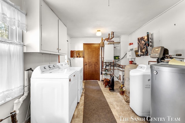 laundry room featuring washing machine and clothes dryer, cabinet space, and water heater