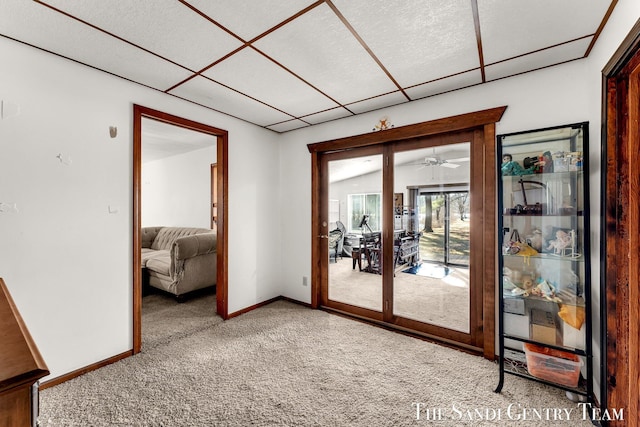 interior space with a drop ceiling, baseboards, and carpet floors