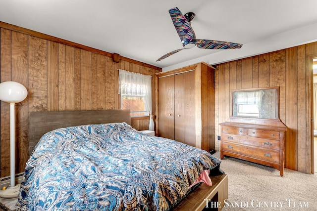 bedroom featuring a closet, carpet flooring, wood walls, and a ceiling fan