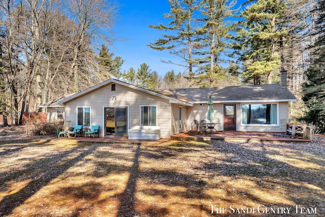 back of property with a chimney and a wooden deck