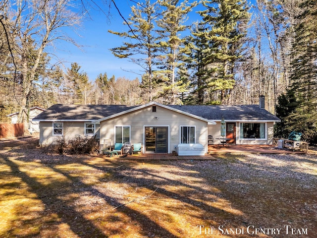 back of house with a wooden deck, a chimney, and a patio