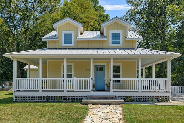 country-style home with covered porch, metal roof, and a front yard