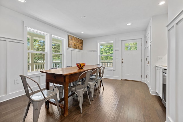 dining room with dark wood finished floors, a decorative wall, and recessed lighting