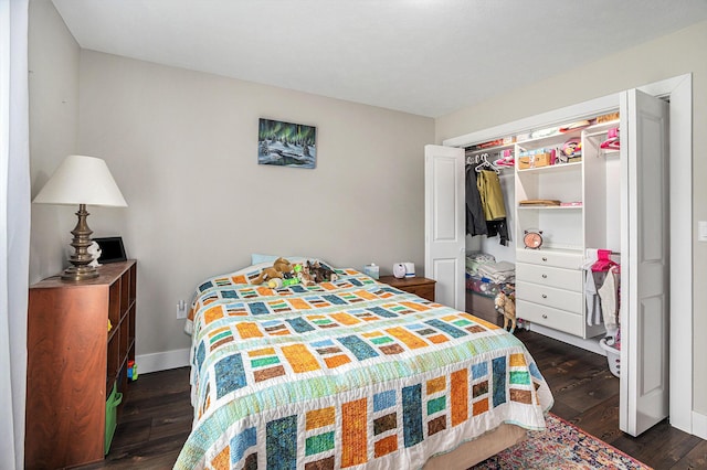 bedroom with dark wood-type flooring, baseboards, and a closet