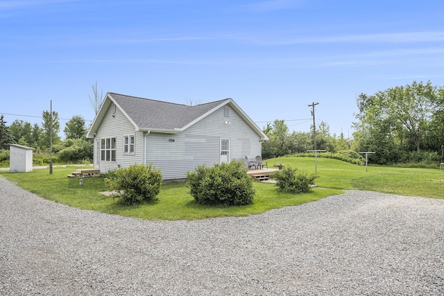 view of home's exterior with a lawn and roof with shingles