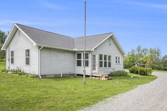 view of home's exterior with a lawn, roof with shingles, and driveway