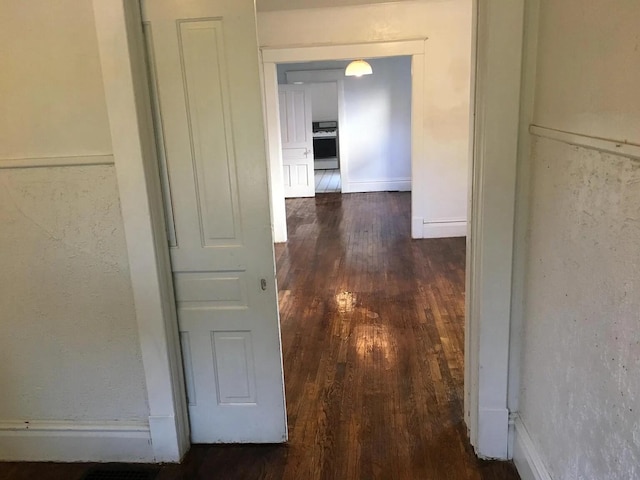 hall with dark wood-type flooring and baseboards