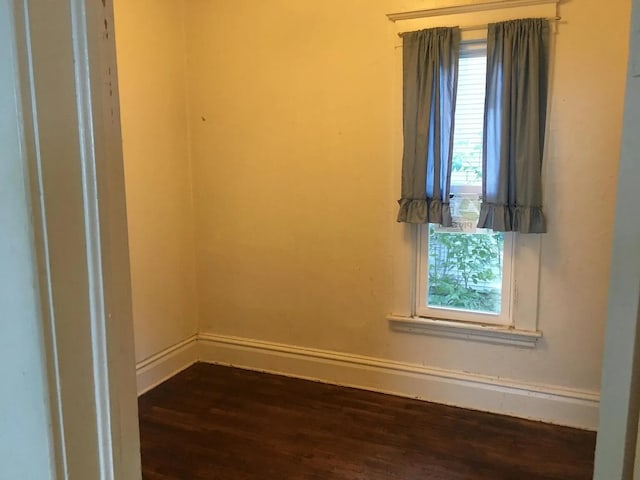 unfurnished room with baseboards and dark wood-type flooring