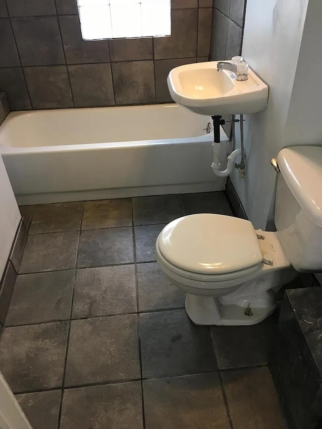 bathroom with toilet, a bathing tub, and a sink