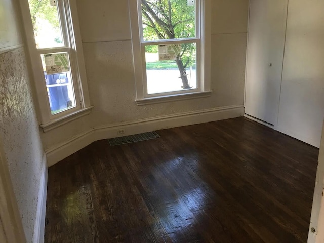 spare room with visible vents, dark wood-type flooring, and a textured wall