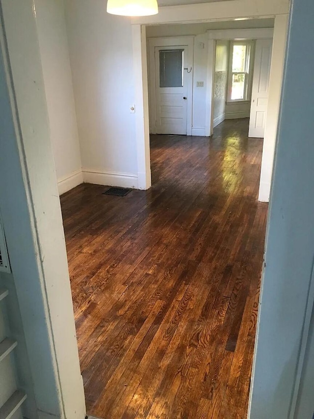 spare room featuring dark wood-style floors and baseboards