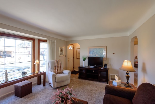 carpeted living area with arched walkways and baseboards