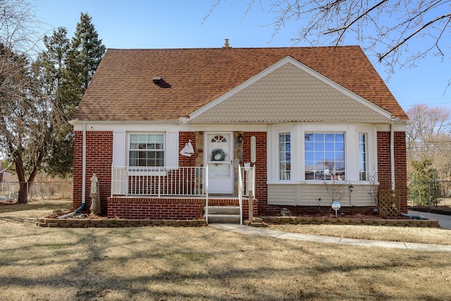 view of front of home with covered porch, brick siding, and a shingled roof