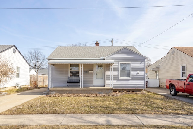 bungalow-style home featuring a chimney, fence, covered porch, and a shingled roof