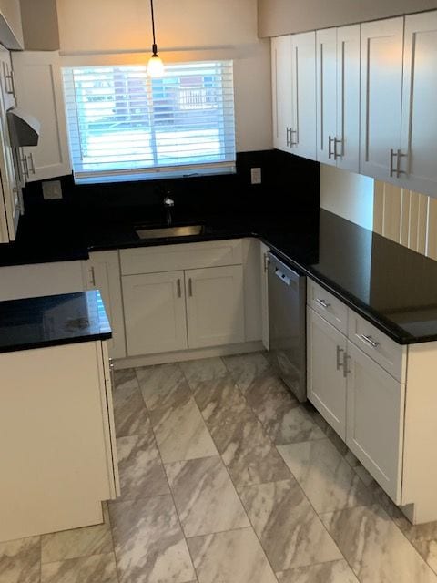 kitchen featuring marble finish floor, a sink, stainless steel dishwasher, dark countertops, and white cabinetry