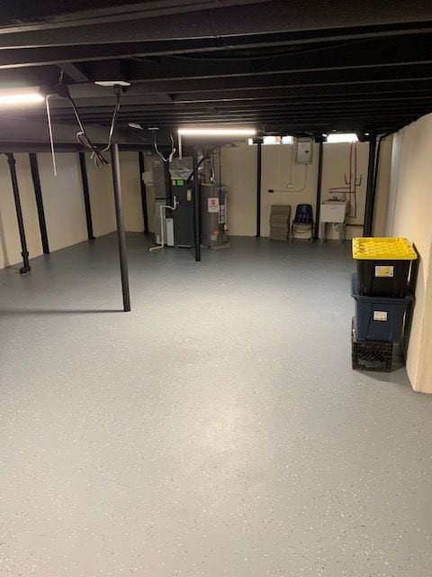 unfinished basement with heating unit, water heater, and a sink