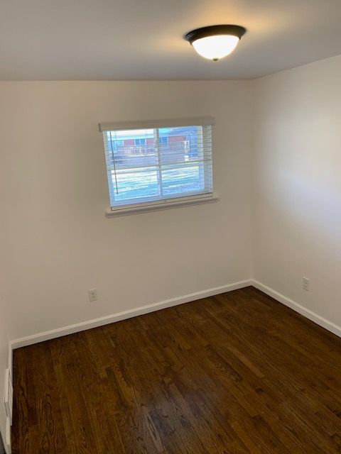 empty room featuring baseboards and dark wood-style flooring