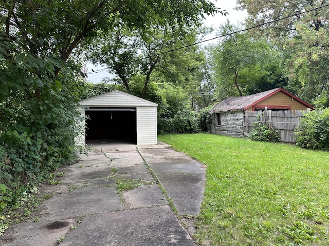 view of yard featuring an outbuilding, driveway, a detached garage, and fence