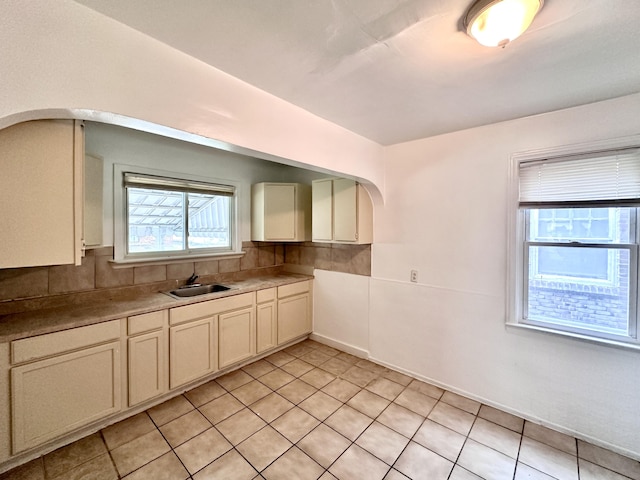 kitchen with light tile patterned flooring, tasteful backsplash, and a sink