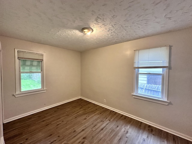 spare room with dark wood-type flooring, baseboards, and a textured ceiling