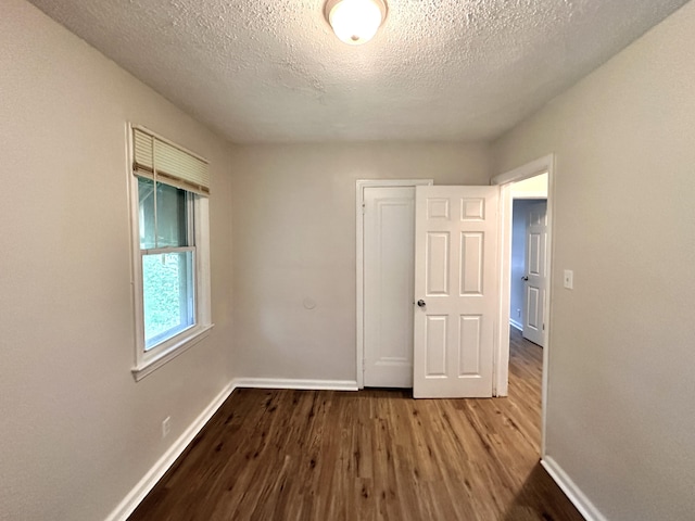 unfurnished bedroom featuring baseboards, a textured ceiling, and wood finished floors