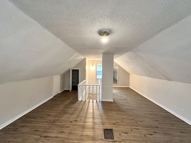 bonus room featuring visible vents, a textured ceiling, wood finished floors, and vaulted ceiling