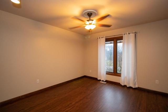 empty room featuring visible vents, a ceiling fan, dark wood-type flooring, and baseboards